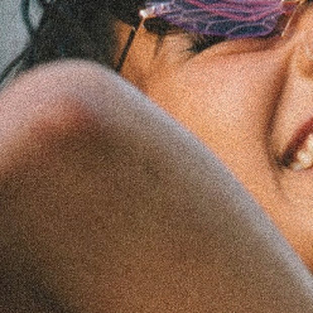 A festivalgoer laughing, head tipped back in the sun.